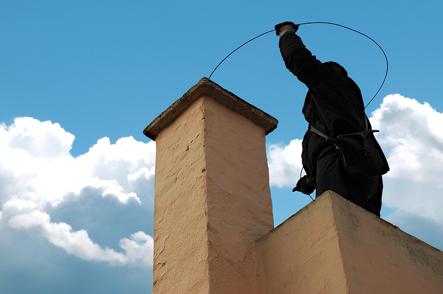 Chimney sweeper on the roof of a house